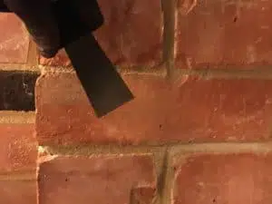 Picture showing brick being scraped following repair with crack repair injection mortar