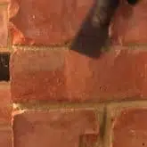 Picture showing brick being scraped following repair with crack repair injection mortar