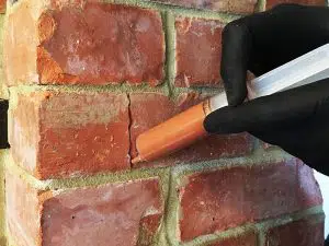 Injecting repair mortar into a fine crack in a brick