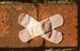 Crakced brick with plasters (bandaid) across crack